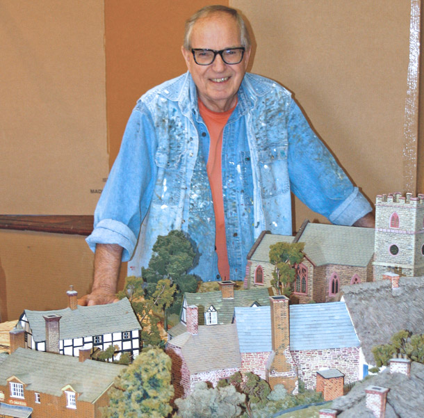 Bill Webb poses with a portion of his model of a pre-WWI English village. 