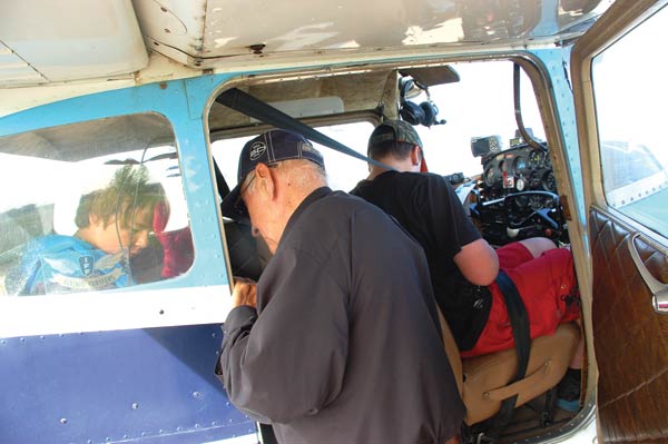 Pilot Stan Chevraux buckles in his next two passengers during the COPA for Kids day.